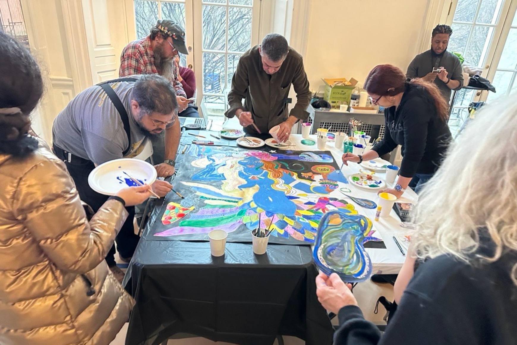 Manny Vega and visitors paint a mermaid portrait together.